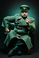 The evil dictator sitting in a chair - obrazy, fototapety, plakaty