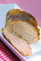 Roast beef on a plate with a red and white checkered tablecloth