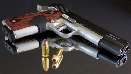 Semi-auto pistol and ammunition on a table with mirrored top.