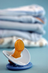 Blue Pacifier and Baby Clothes
