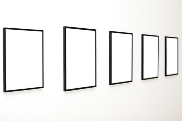 Five empty frames on white wall exhibition