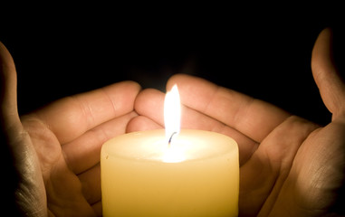 Hands trying to save the candle light
