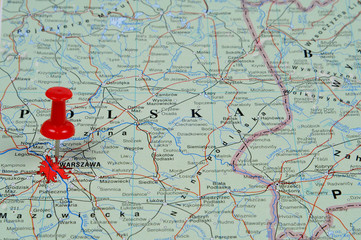 Pin pointing Warsaw on polish map in atlas