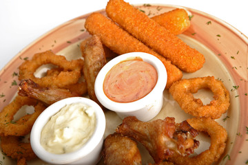 Rings of a squid, fish sticks, chicken hips with sauce.