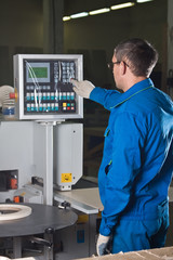 The worker presses buttons of the panel of the machine tool