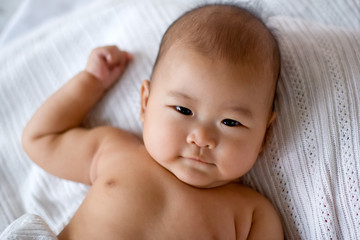 Baby lying on bed, looking straight at camera