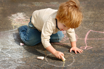 Naklejka premium Boy drawing outside with chalk