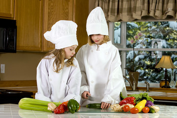 two young cooks cutting vegetables