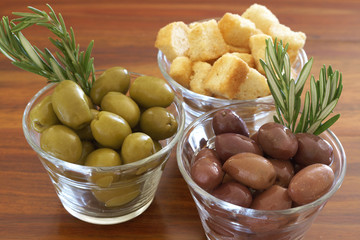 Two jars of green and black olives and croutons