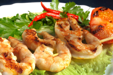 Grilled prawns on bamboo sticks served on lettice