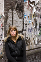 Young Adult Woman Standing Against Torn Advertisements