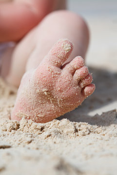 baby toddler feet with sand on sunny beach