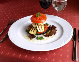 Dish of Italian cuisine -  vegetables tower on red tablecloth