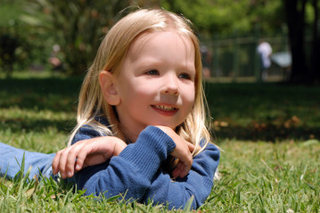 The little girl laying on a grass in park