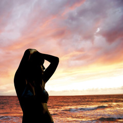 young girl silhouette on sunset sea background