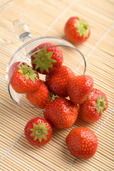 ripe strawberries falling from glass bowl