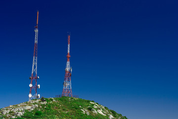 Telecommunication tower on the green field with blue sky