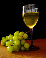 White grapes and glass of wine, on black