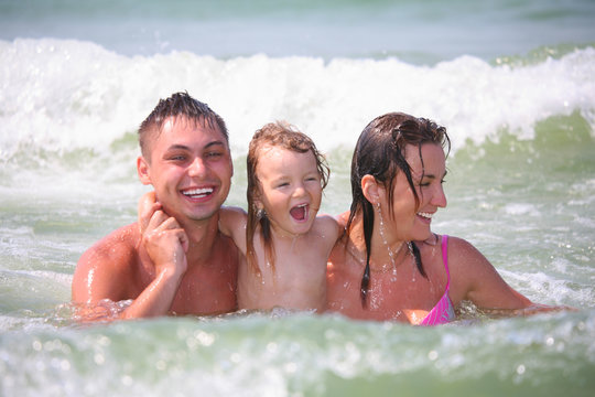 family with little girl in waves