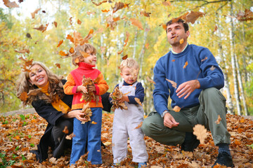 family of four throw autumnal leaves