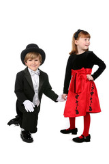 young boy in tuxedo kneeling and holding hand of little girl