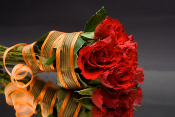 red roses with orange ribbon against the black background