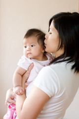 Mother carrying and kissing baby on forehead.