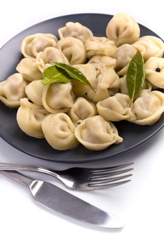 ravioli on a dark plate with fork and knife