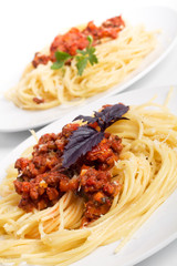 two servings of spaghetti with bolognese sauce, cheese and basil