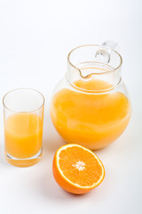 fresh orange juice in a jug and glass with half of an orange