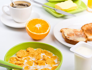 breakfast with cornflakes, two toasts, an orange and coffee