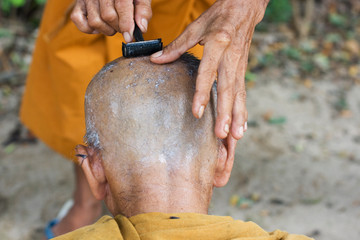 monk getting head shaved by fellow monk