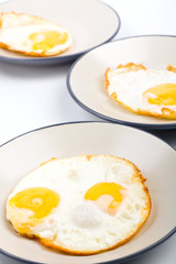 four fried eggs on three plates