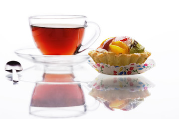 black tea in a glass cup and a fruit tart with reflections