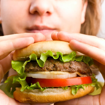 A Young Man Holding A Hamburger