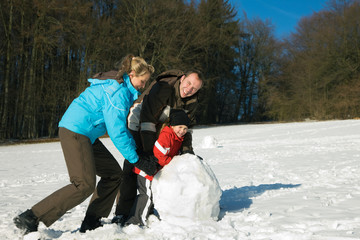 Familie mit Kindern baut Schneemann