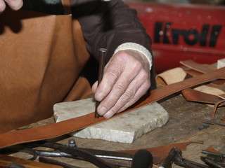 Artesano haciendo los agujeros de un cinturon de cuero
