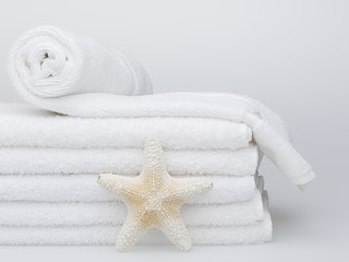 Obraz na płótnie Canvas Assorted towels and starfish against a white background