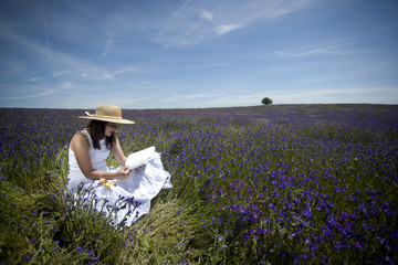 young woman in white dress reading book outdoors