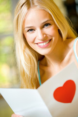 Young attractive happy woman, reading valentine card
