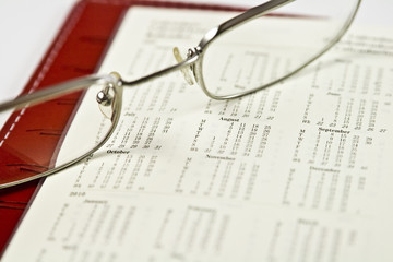 eyeglasses resting on a planner's full calendar