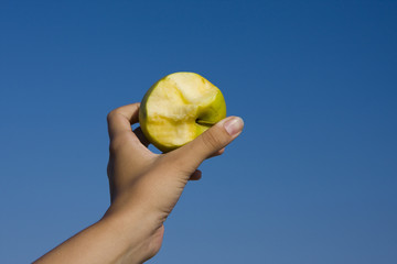 apple in girl's hand over blue sky