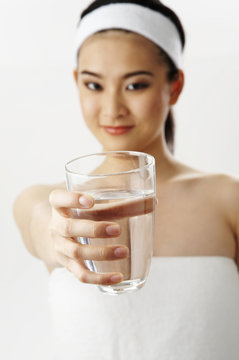 woman in towel show a glass of water