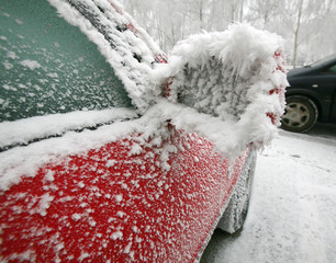Red car with outside mirror covered of icing