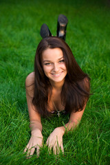 Beautiful young brunette rests on the green grass