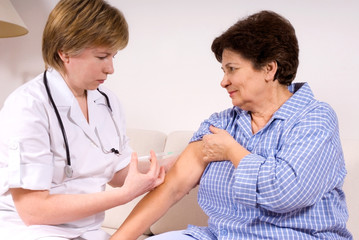 Doctor giving an injection to a senior female