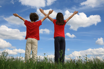 Kids holding arms up in praise against blue sky