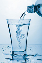 pure water splashing from bottle into glass