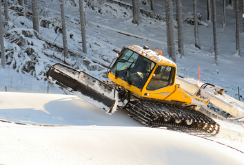 Ski slope with a yellow ratrak doing track maintenance