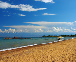 Sandy beach with a pier against the blue sky
